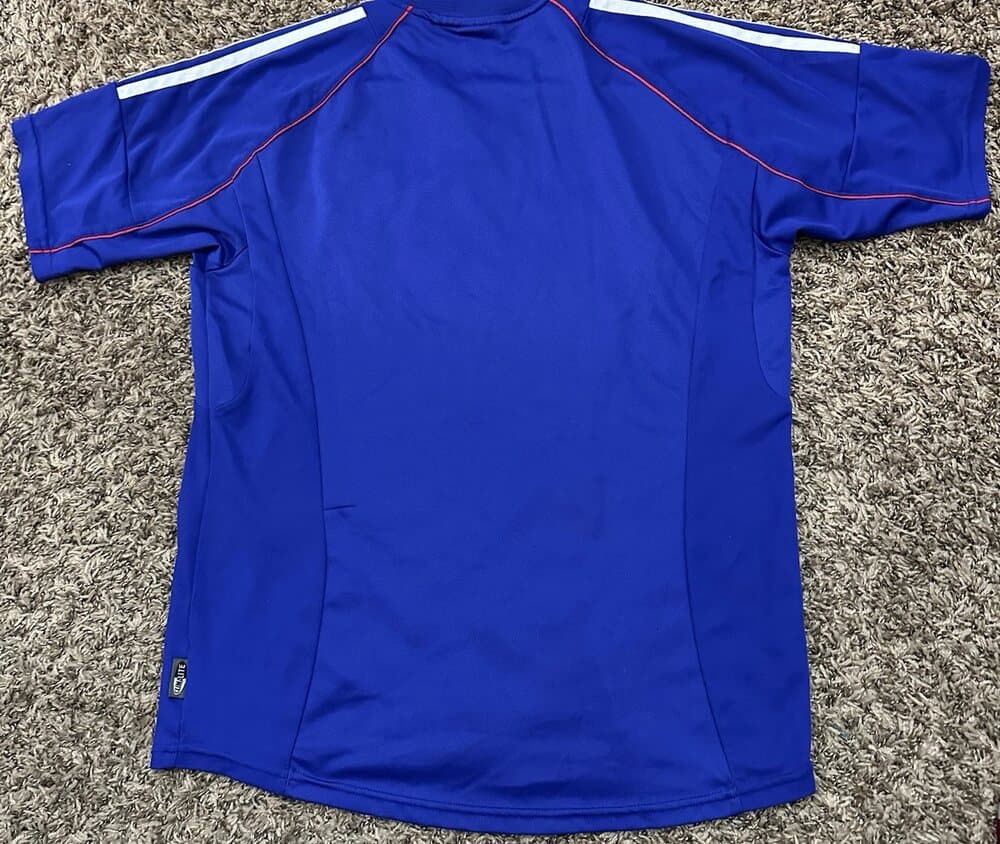 Japan 2002 home shirt, back: royal blue with white adidas shoulder stripes and red trim.