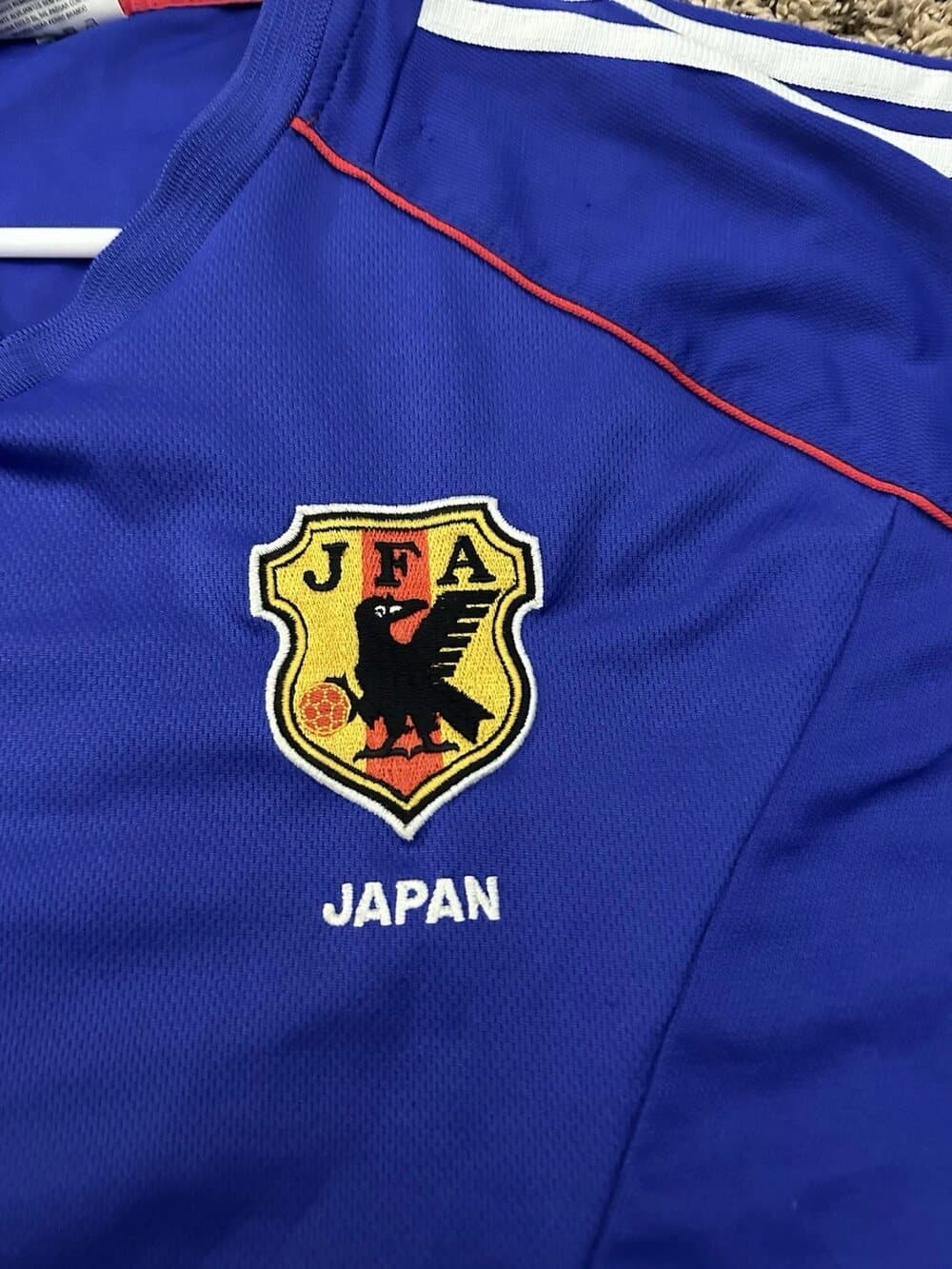 Japan 2002 home shirt detail: the JFA Yatagarasu crest and JAPAN wordmark on the royal-blue body.