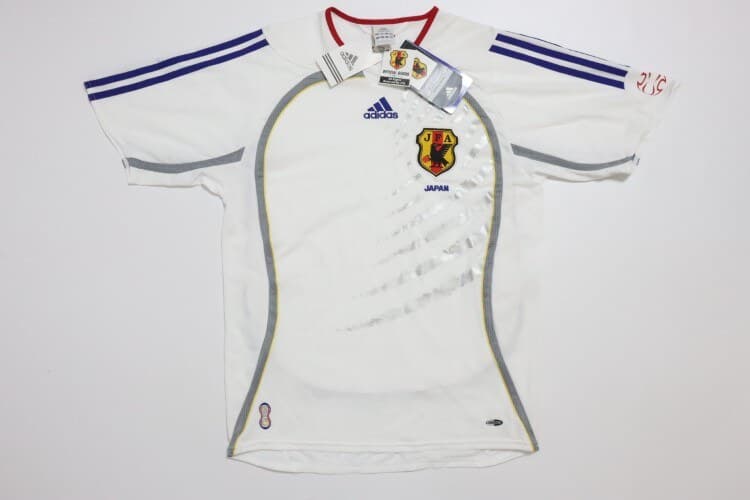 Japan 2006 away shirt, front: white with a subtle tonal graphic, blue adidas stripes, red trim and the JFA crest.